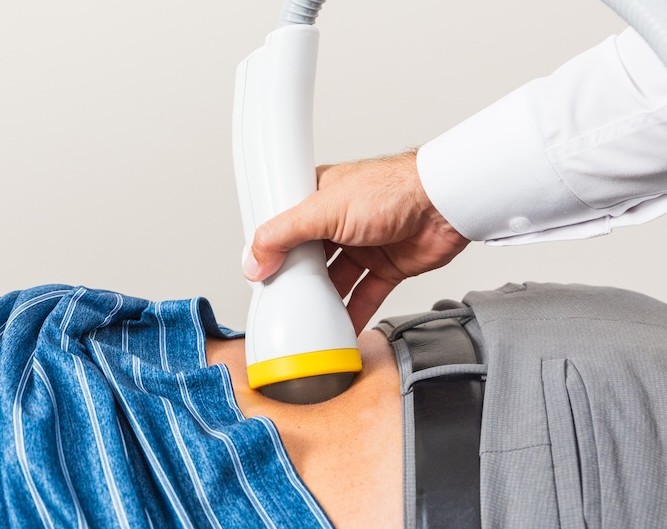 A Thrive Health Center chiropractor applies SoftWave therapy to a patient's back for slipped disk treatment in Jacksonville.
